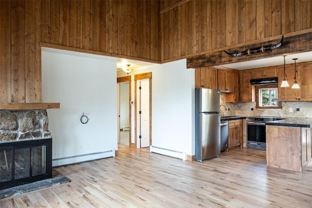602 Ryan Gulch Rd Unit B, Silverthorne, CO 80498 - kitchen with appliances with stainless steel finishes, a baseboard radiator, decorative backsplash, light wood-style floors, and wood walls