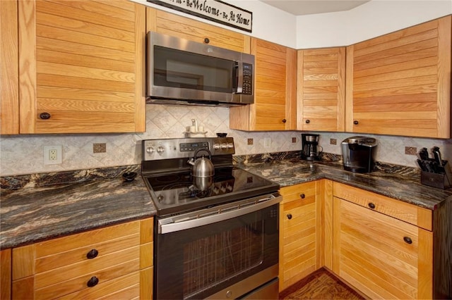 kitchen featuring appliances with stainless steel finishes, dark stone countertops, and decorative backsplash