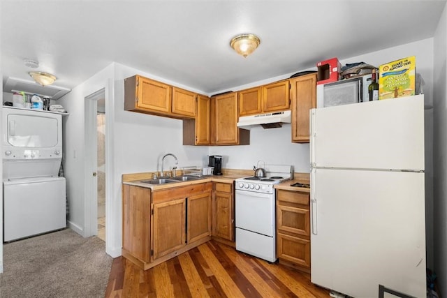kitchen featuring stacked washer / dryer, under cabinet range hood, light countertops, a sink, and white appliances