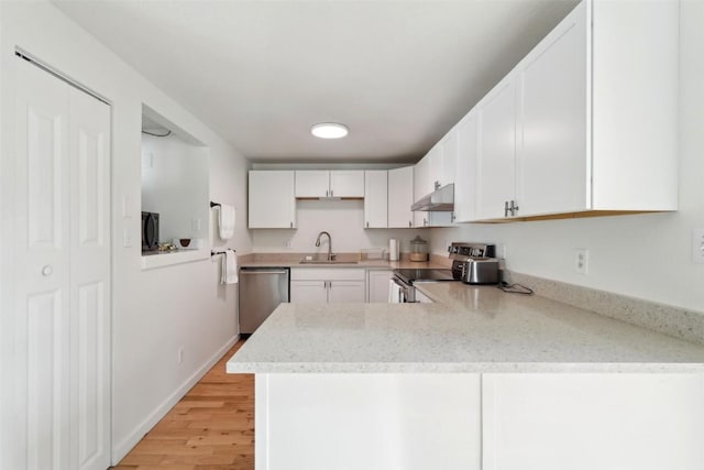 kitchen featuring white cabinets, stainless steel appliances, a peninsula, a sink, and under cabinet range hood