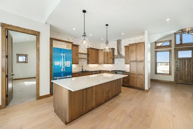 kitchen featuring a spacious island, light wood-type flooring, wall chimney exhaust hood, and high end refrigerator