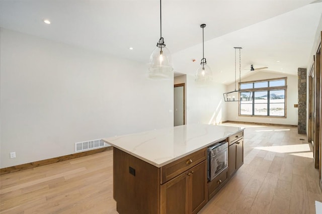 kitchen featuring built in microwave, light wood-style floors, visible vents, and open floor plan