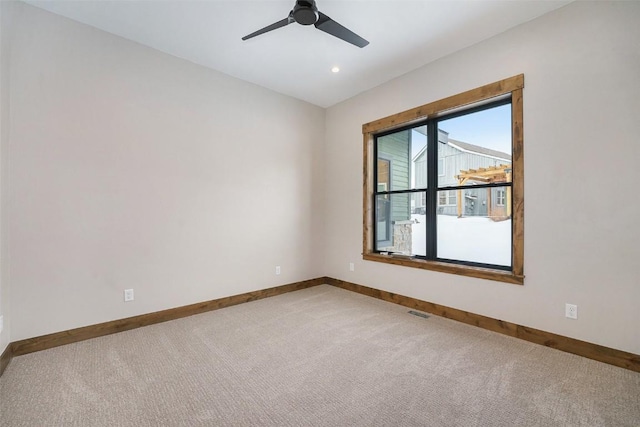 empty room featuring baseboards, ceiling fan, and light colored carpet