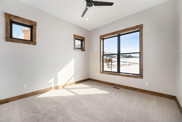 empty room with ceiling fan, visible vents, baseboards, and light carpet