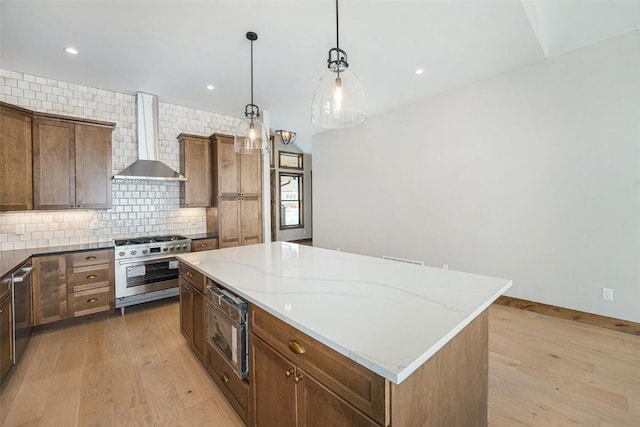 kitchen with wall chimney exhaust hood, a center island, stainless steel appliances, and light wood-style floors