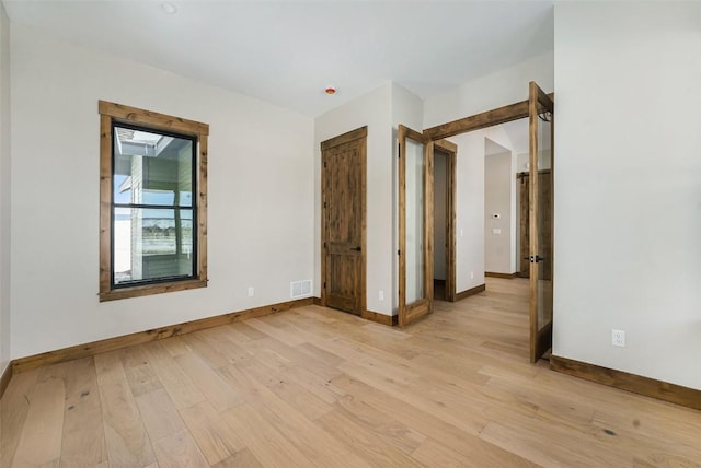 unfurnished bedroom with light wood-style floors, visible vents, and baseboards