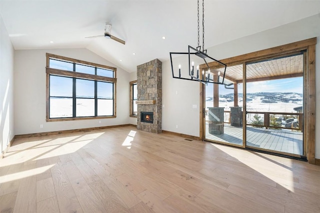 unfurnished living room with light wood-style flooring, a healthy amount of sunlight, baseboards, and ceiling fan with notable chandelier