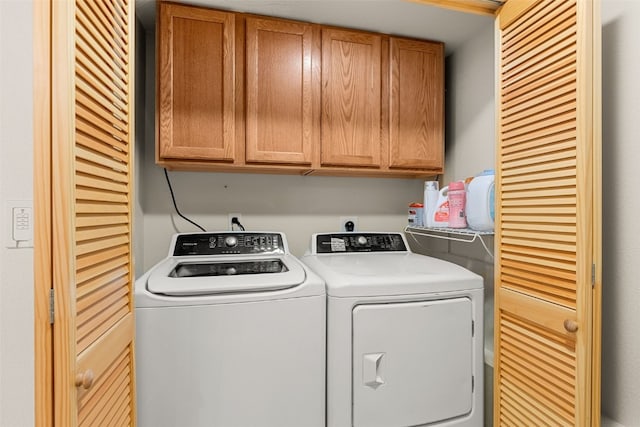 clothes washing area featuring independent washer and dryer and cabinet space