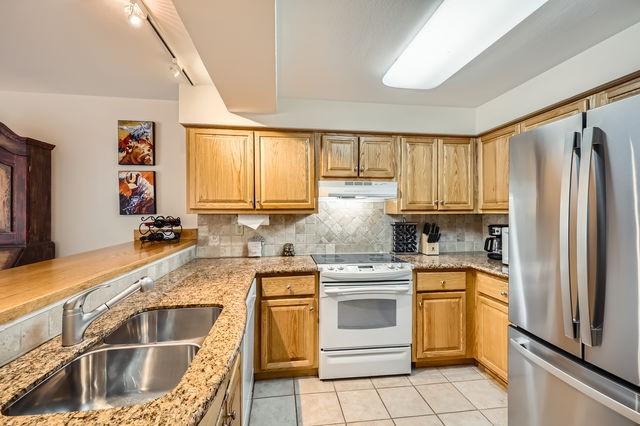 755 Columbine Rd Unit 303, Breckenridge, CO 80424 - kitchen featuring freestanding refrigerator, white electric stove, a sink, under cabinet range hood, and light stone countertops