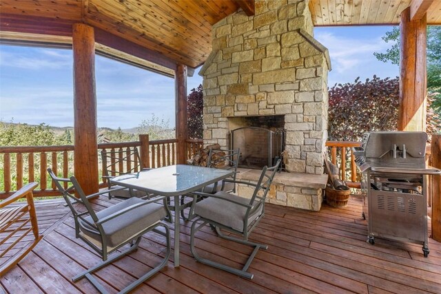 wooden deck featuring outdoor dining area and an outdoor stone fireplace