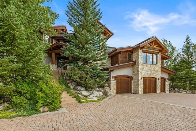 view of front facade featuring decorative driveway, stucco siding, stairway, a garage, and stone siding