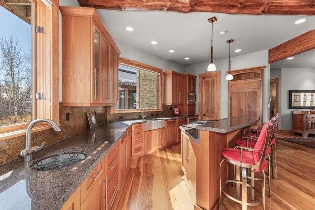 kitchen featuring hanging light fixtures, a kitchen island, glass insert cabinets, and dark stone countertops