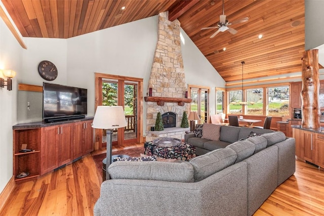 living room with high vaulted ceiling, a stone fireplace, wooden ceiling, light wood-style flooring, and beamed ceiling