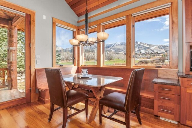 dining room featuring lofted ceiling, light wood finished floors, breakfast area, and a mountain view