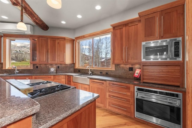 kitchen with appliances with stainless steel finishes, tasteful backsplash, a sink, and a wall mounted AC