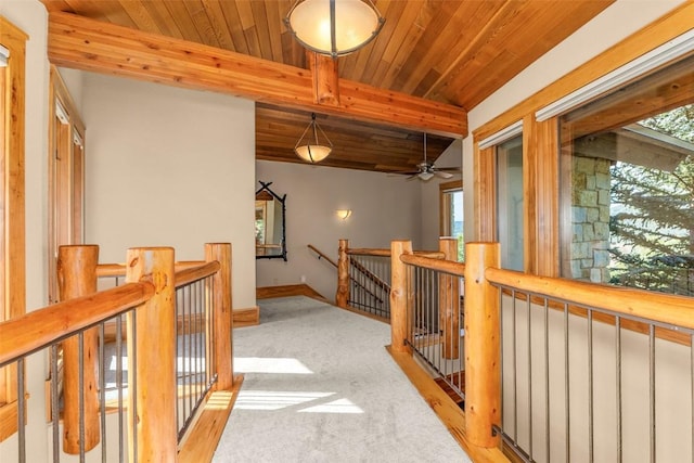 hall with vaulted ceiling with beams, light colored carpet, wood ceiling, an upstairs landing, and baseboards