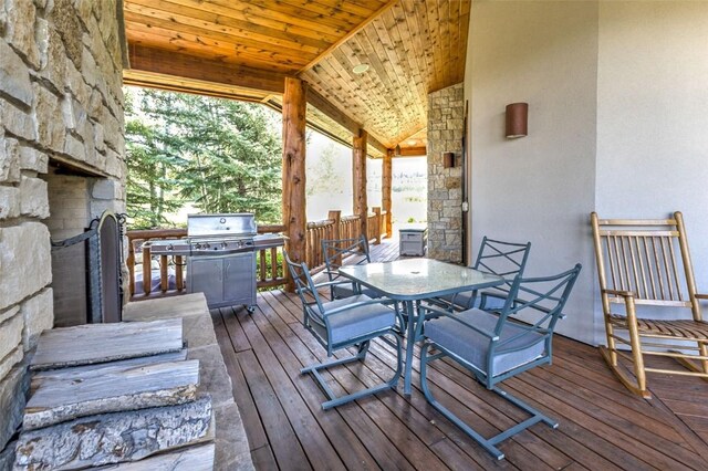 wooden deck with outdoor dining area, an outdoor stone fireplace, and grilling area