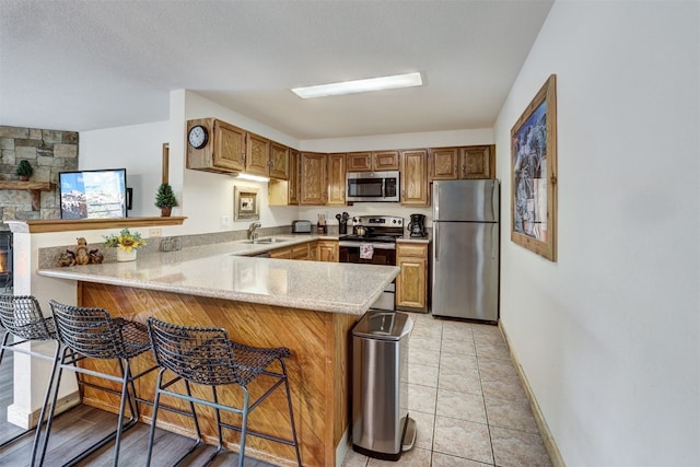 23034 US Highway 6 Unit 203, Dillon, CO 80435 - kitchen with stainless steel appliances, a peninsula, baseboards, a sink, and a kitchen bar
