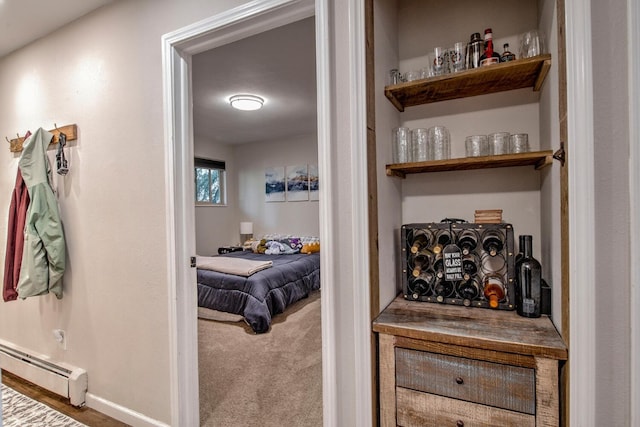 hall featuring a baseboard heating unit, baseboards, and carpet