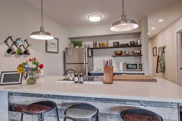 2442 Ryan Gulch Ct Unit 204, Silverthorne, CO 80498 - kitchen with appliances with stainless steel finishes, a kitchen bar, light countertops, tasteful backsplash, and hanging light fixtures