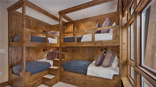 bedroom with wooden walls and beam ceiling