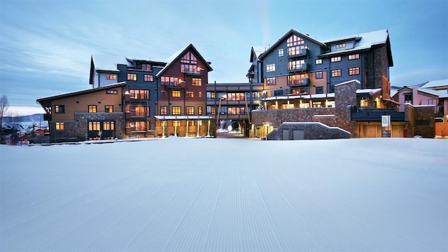 snow covered property with stone siding