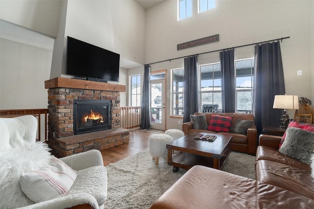 living room with a stone fireplace, hardwood / wood-style floors, a high ceiling, and a wealth of natural light