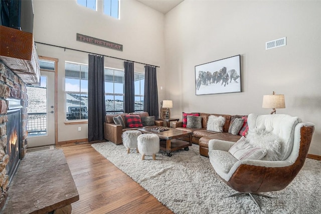 living room with a fireplace, a towering ceiling, and wood-type flooring