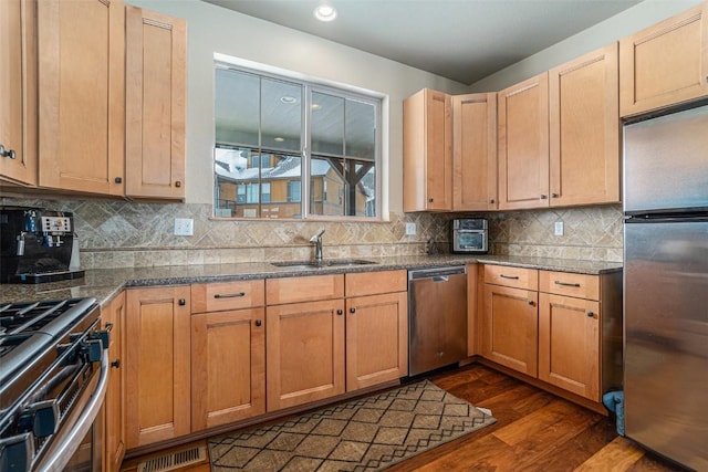 kitchen with appliances with stainless steel finishes, dark hardwood / wood-style flooring, sink, and backsplash