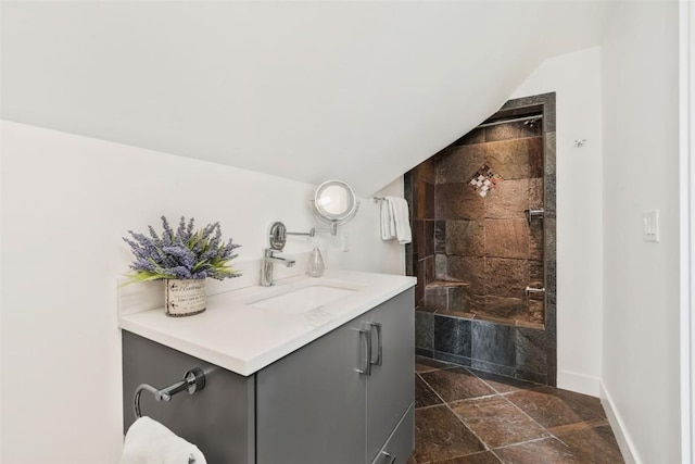 24 Maple St, Steamboat Springs, CO 80487 - bathroom with baseboards, tiled shower, stone tile flooring, vanity, and vaulted ceiling