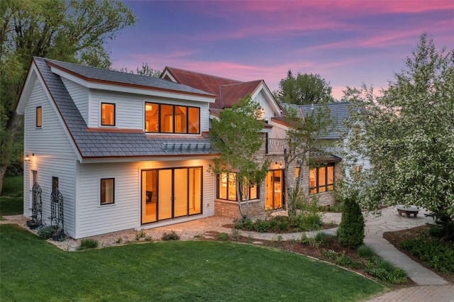 24 Maple St, Steamboat Springs, CO 80487 - back of house at dusk featuring a lawn and a patio
