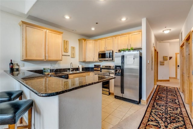 135 Main St Unit 202, Dillon, CO 80435 - kitchen featuring appliances with stainless steel finishes, light brown cabinetry, a peninsula, dark stone countertops, and recessed lighting