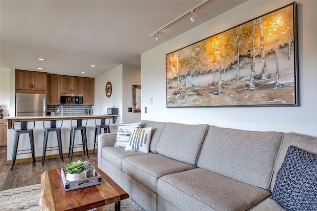 living room with recessed lighting, wood finished floors, and rail lighting