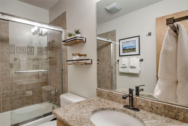 full bathroom with a textured ceiling, combined bath / shower with glass door, toilet, and vanity