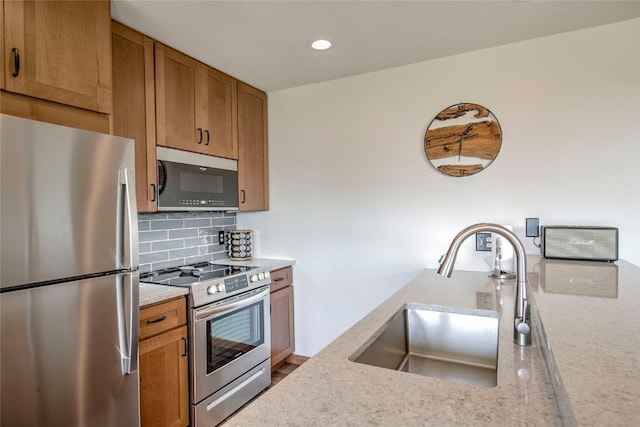 kitchen with a sink, recessed lighting, decorative backsplash, brown cabinets, and appliances with stainless steel finishes