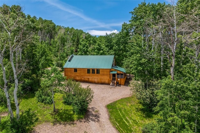 389 Routt Forest Loop, Craig, CO 81625 - back of property with driveway, a metal roof, and a wooded view