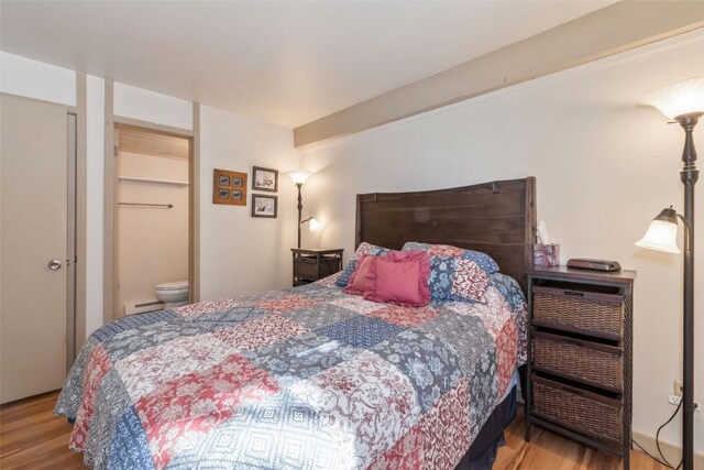 bedroom with wood finished floors and baseboard heating