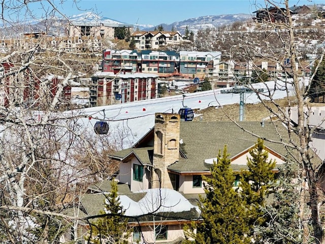 snowy aerial view featuring a residential view and a mountain view