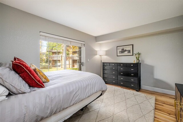 bedroom featuring light wood-type flooring, baseboards, and access to outside