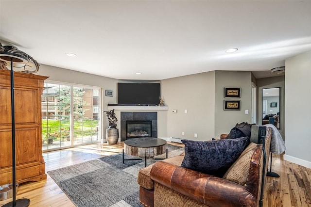 living area featuring recessed lighting, a fireplace, light wood finished floors, and baseboards