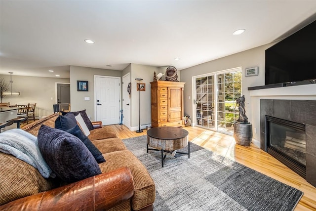 living room with recessed lighting, a tile fireplace, baseboards, and wood finished floors