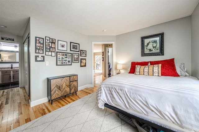 bedroom with light wood-style flooring, baseboards, and a sink