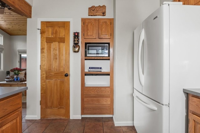 1763 Brome Dr, Steamboat Springs, CO 80487 - kitchen with freestanding refrigerator, stainless steel microwave, dark tile patterned floors, baseboards, and wooden ceiling