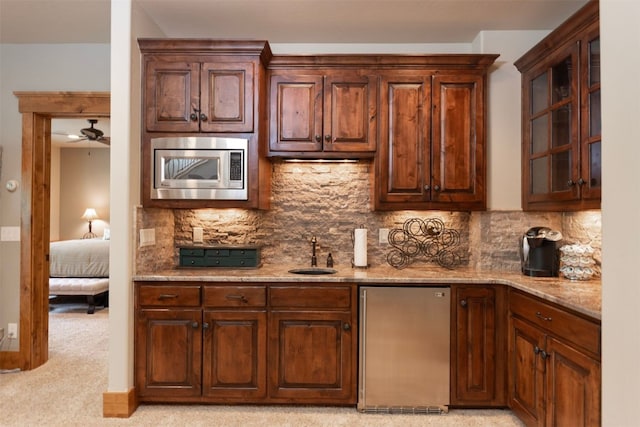 460 Two Cabins Dr, Silverthorne, CO 80498 - kitchen with appliances with stainless steel finishes, decorative backsplash, light stone counters, glass insert cabinets, and a ceiling fan