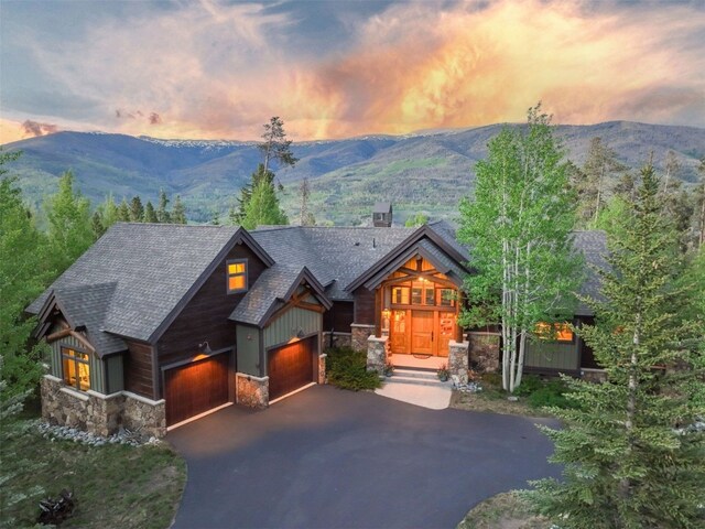 460 Two Cabins Dr, Silverthorne, CO 80498 - view of front facade with stone siding, a mountain view, driveway, a garage, and roof with shingles
