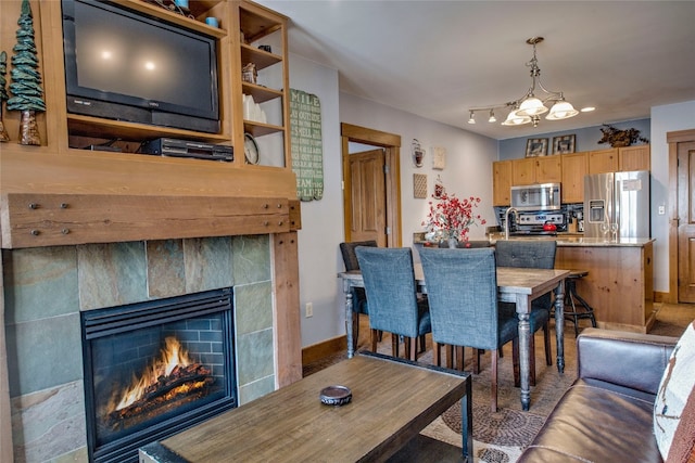 dining room featuring a tiled fireplace, baseboards, and an inviting chandelier