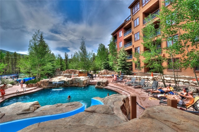 pool with a patio area and fence