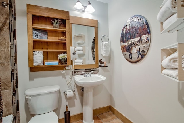 bathroom with toilet, a sink, and baseboards