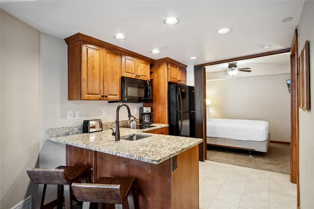 640 Village Rd Unit 4326, Breckenridge, CO 80424 - kitchen featuring light stone countertops, a breakfast bar area, brown cabinetry, visible vents, and black appliances