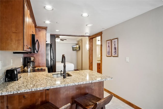 640 Village Rd Unit 4326, Breckenridge, CO 80424 - kitchen with light stone countertops, brown cabinets, a sink, black appliances, and a peninsula